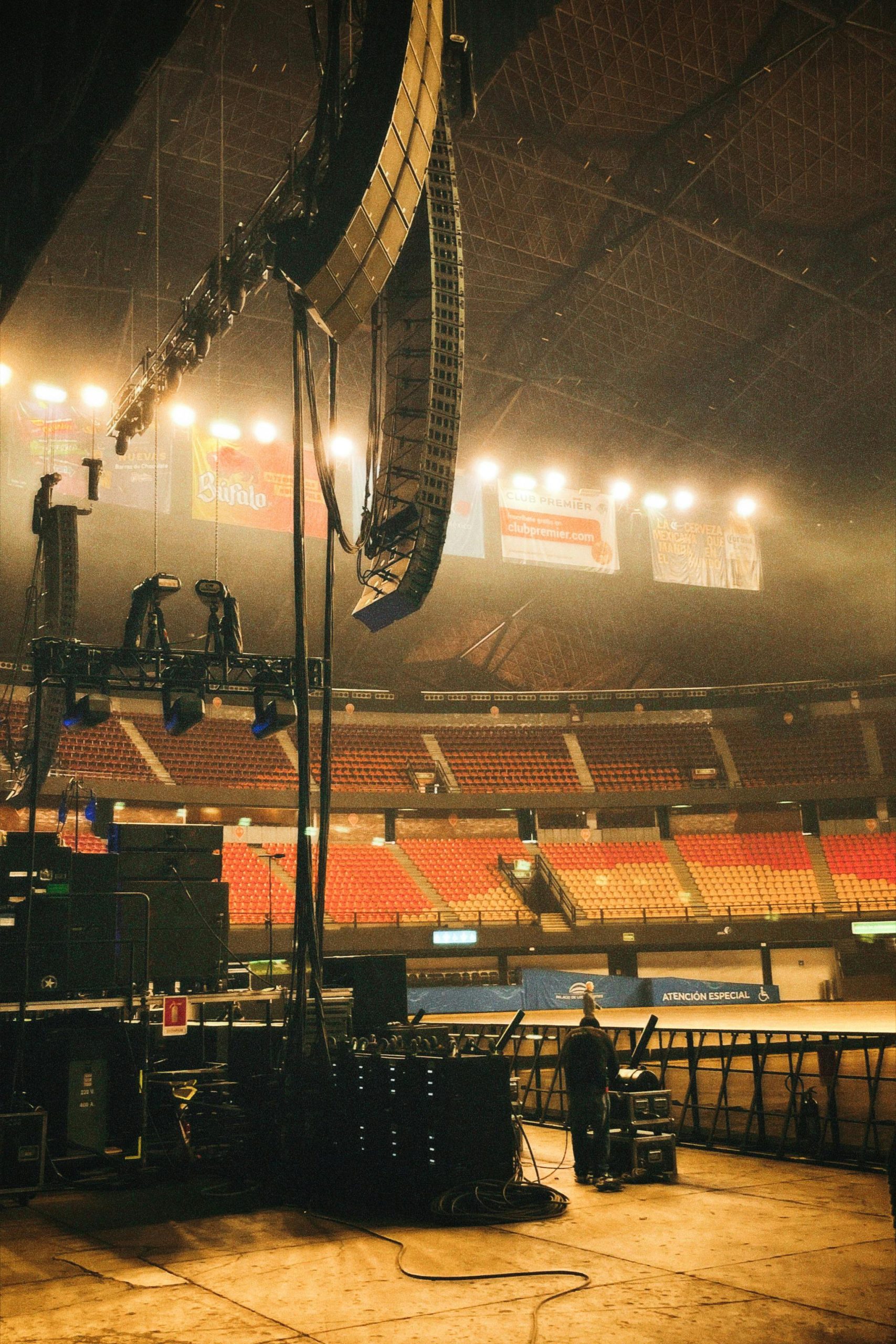 Empty stadium with stage lighting and seating, ready for a concert.